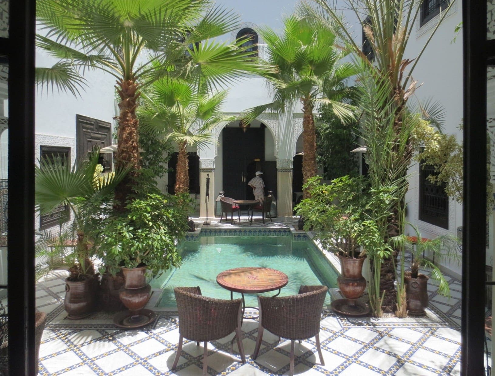 A palm-filled courtyard and plunge pool inside a traditional Marrakech riad
